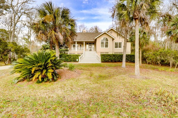 A two-story house with a front porch, surrounded by palm trees and a well-maintained lawn.