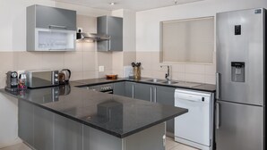 Una cocina moderna con una isla central, electrodomésticos de acero inoxidable y una ventana con persianas.