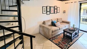 Ein Wohnzimmer mit einer Couch, einem Couchtisch und einer Treppe.