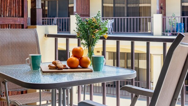 Ein Balkon mit Tisch, der mit Orangen, einer Blumenvase und einer Auswahl an Gebäck dekoriert ist.