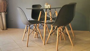 Ein Essbereich mit Tisch und vier Stühlen, einer Vase mit Trockenpflanzen und einem 'Welcome'-Schild.