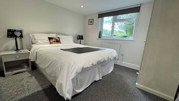 A bedroom with a large bed, two bedside tables, a window with a view, and a radiator.