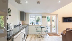 Cocina moderna con lavadora, cafetera y comedor con mesa y sillas.