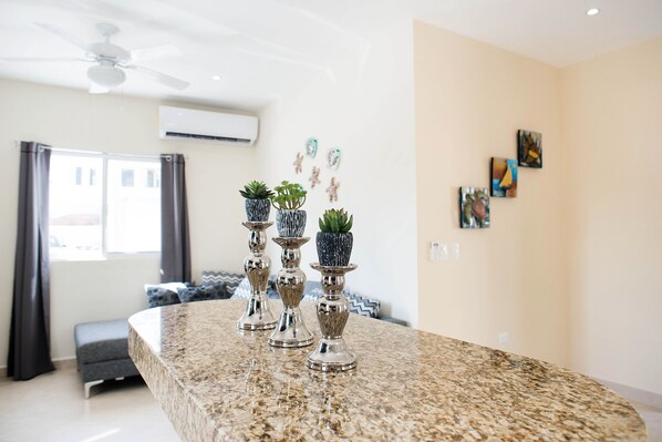 A kitchen with granite countertops, a ceiling fan, and decorative vases with plants.