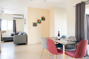 A modern living room with a sofa, dining table, chairs, and artwork on the wall.