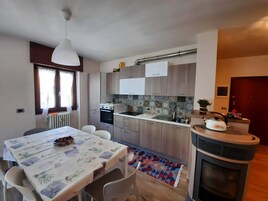 Cocina compacta con electrodomésticos modernos, una mesa de comedor con sillas y una chimenea.