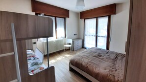 Quarto com uma cama, uma escrivaninha, uma cadeira e um radiador.