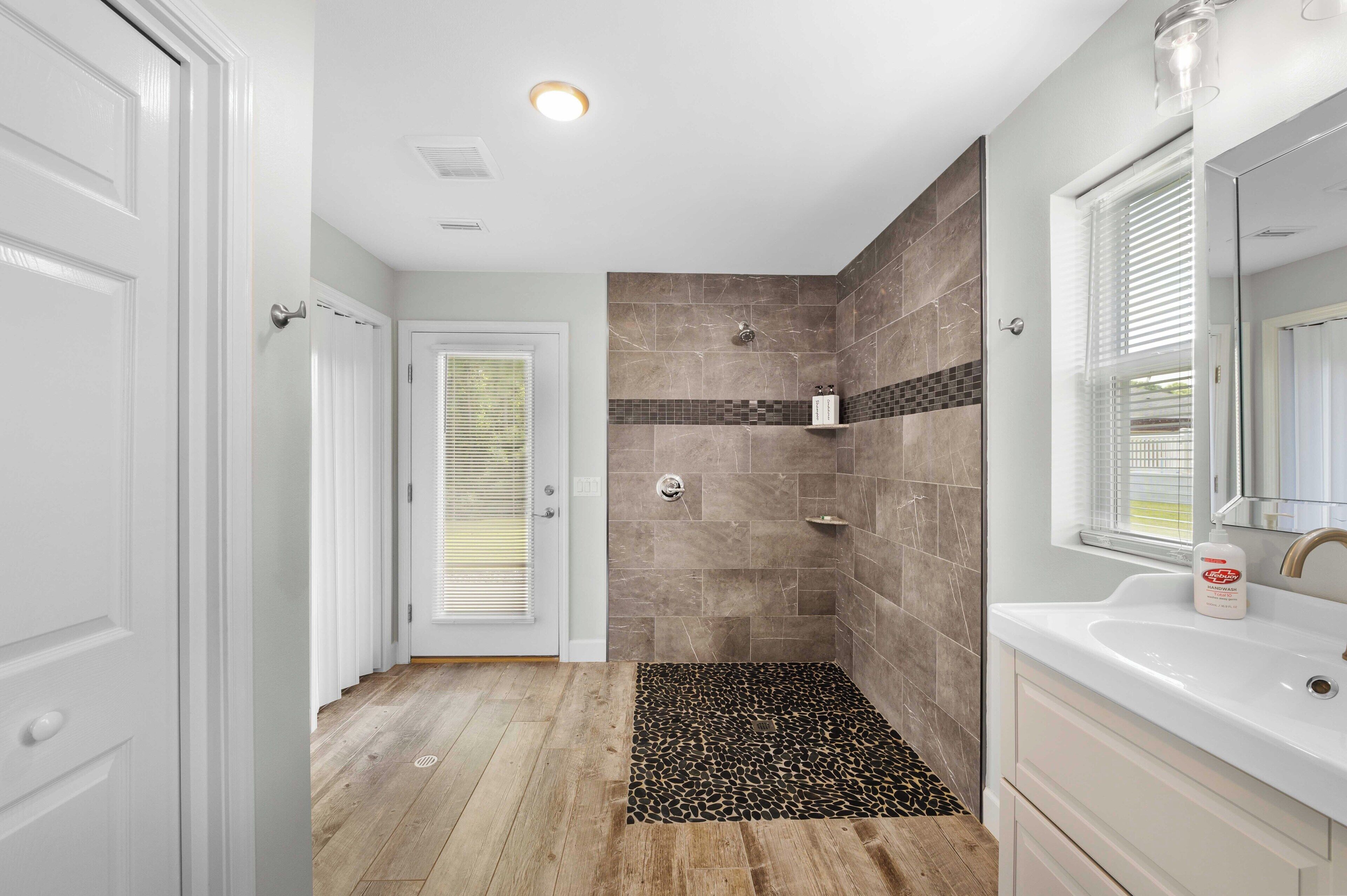 Une salle de bain avec une douche, un lavabo et un miroir.