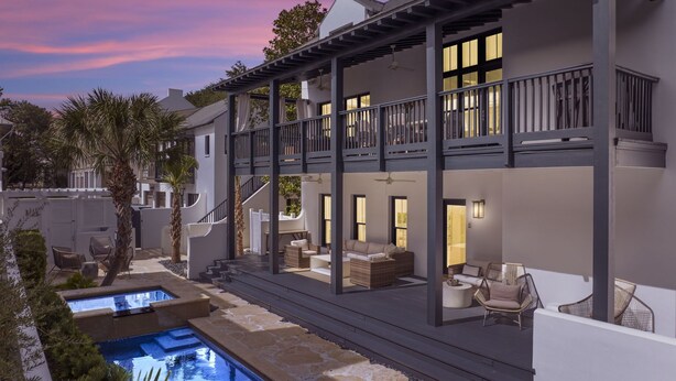Ein modernes Haus mit zwei Etagen, einem Pool, Sitzgelegenheiten im Freien und einem Balkon.