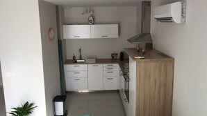 A compact kitchen with white cabinets, a wooden countertop, and an air conditioning unit.