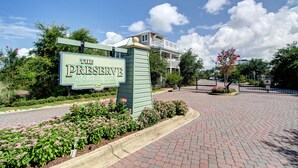A sign for 'The Preserve at Graton Beach' with a brick pathway and landscaped flower beds. - Cute little Cottage! Perfect Getaway! 2 Pools! SLEEPS 4 w/ BEACH CHAIRS! (Santa Rosa Beach)
