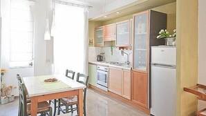 Eine kompakte Küche mit Holzausbau, einem weißen Kühlschrank und einem Essbereich mit Tisch und Stühlen.
