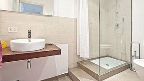 Ein Badezimmer mit einem weißen Waschbecken, einer Duschkabine aus Glas und einer Toilette.