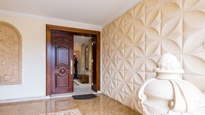 A hallway with a wooden door, a decorative wall with geometric patterns, and a white sculpture. - Imagine Renting Your Own 5 Star Private Cyprus Villa on the Beach, Paphos Villa 1410 (Ayia Marina Chrysochous)