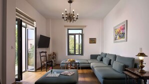 A modern living room with a sectional sofa, a round coffee table, and a chandelier. - Muazzo Historic Residence, a modernized gem (Pigi, Rethymno)