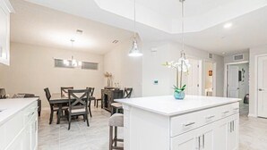 A modern kitchen with white cabinetry, a central island, and pendant lighting. - Spacious End-Unit Condo | Modern Open Floor Plan w/ Elegant Décor & Full Comfort | Minutes to Disney (Kissimmee)