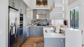 Een moderne keuken met roestvrijstalen apparatuur, grijze kastjes en een groot eiland met een spoelbak.