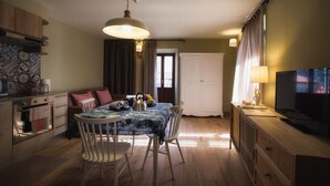A cozy kitchen with a dining table, chairs, and a TV on a wooden cabinet. - La Maison Du Lac Iseo - apt B (Predore)