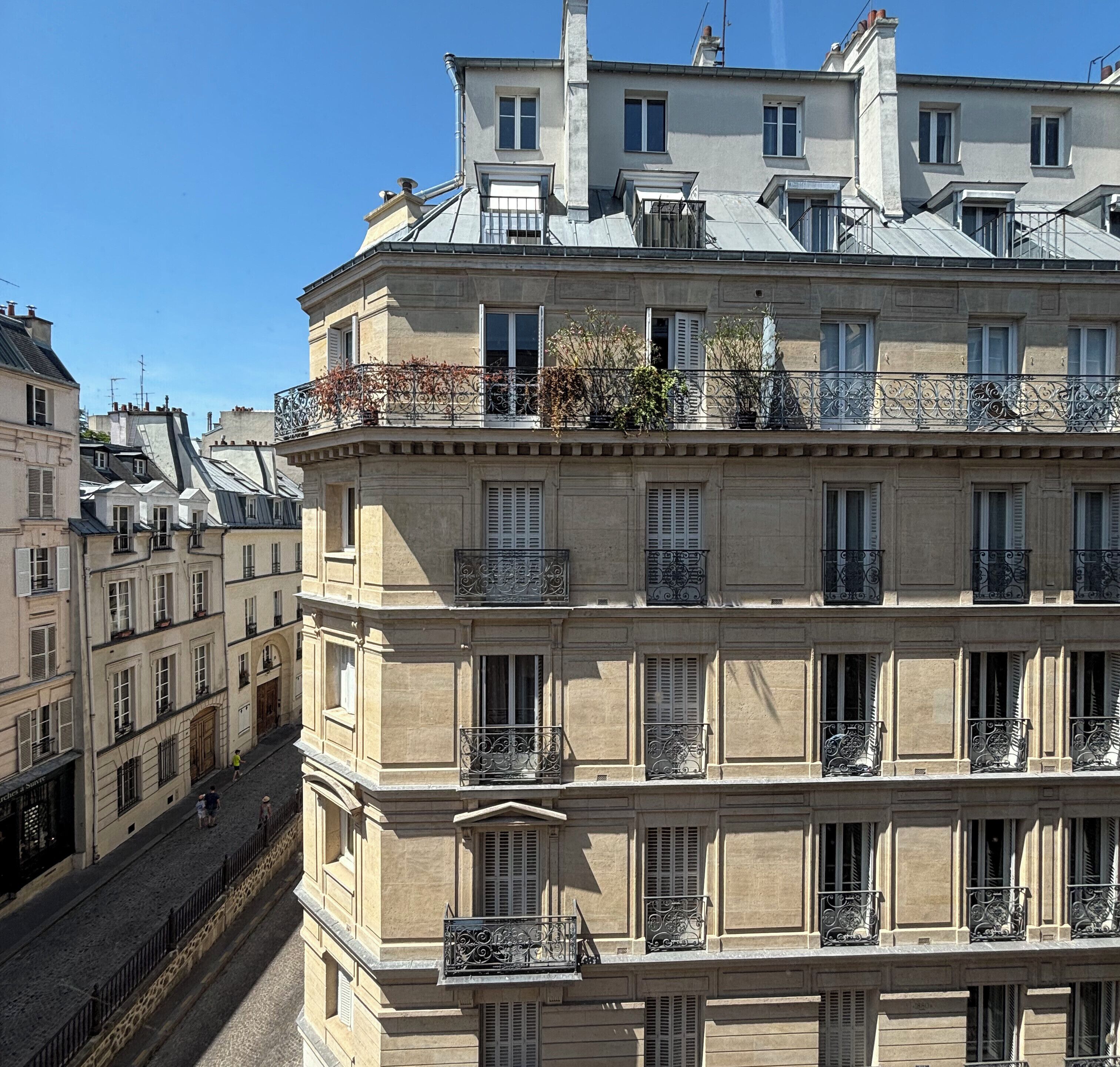 A multi-story building with balconies, large windows, and a stone facade.