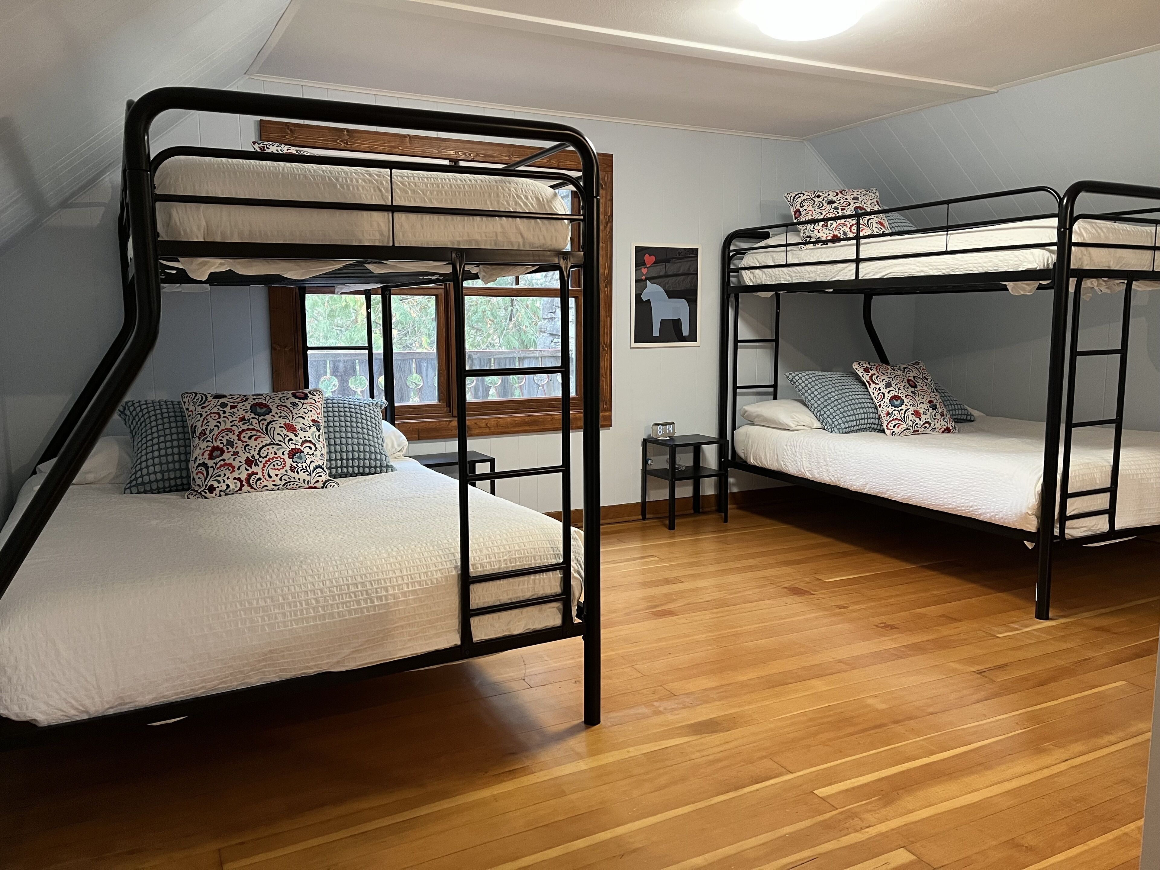 Dos literas en una habitación con suelo de madera y una ventana.