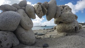 A beach with large, porous rocks stacked in a natural formation.