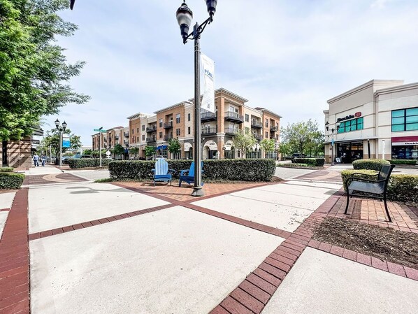 A pedestrian walkway with benches, a lamp post, and a building with multiple floors and balconies. - A bike ride from the beach (Wilmington)