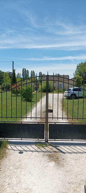 Una entrada con portón y un sendero de grava que conduce a un coche estacionado.