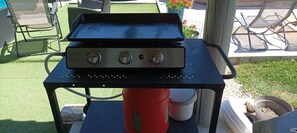 Una instalación de parrilla al aire libre sobre una mesa, con una manguera conectada.