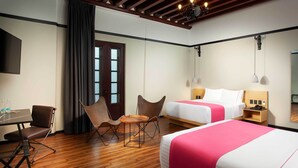 A hotel room with two beds, a desk with chairs, a wooden floor, and a large mirror. - Hotel MX mas centro CDMX, Trademark Collection by Wyndham (Mexico City)