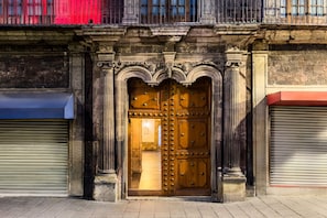 A large wooden door with ornate carvings and a metal grille, flanked by two closed shutters. - Hotel MX mas centro CDMX, Trademark Collection by Wyndham (Mexico City)