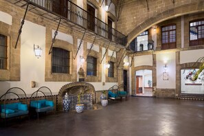 A spacious interior with a high ceiling, stone walls, and a central courtyard. - Hotel MX mas centro CDMX, Trademark Collection by Wyndham (Mexico City)