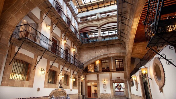 A multi-level atrium with stone arches, balconies, and decorative lighting. - Hotel MX mas centro CDMX, Trademark Collection by Wyndham (Mexico City)