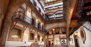 A multi-level atrium with stone arches, balconies, and decorative lighting. - Hotel MX mas centro CDMX, Trademark Collection by Wyndham (Mexico City)