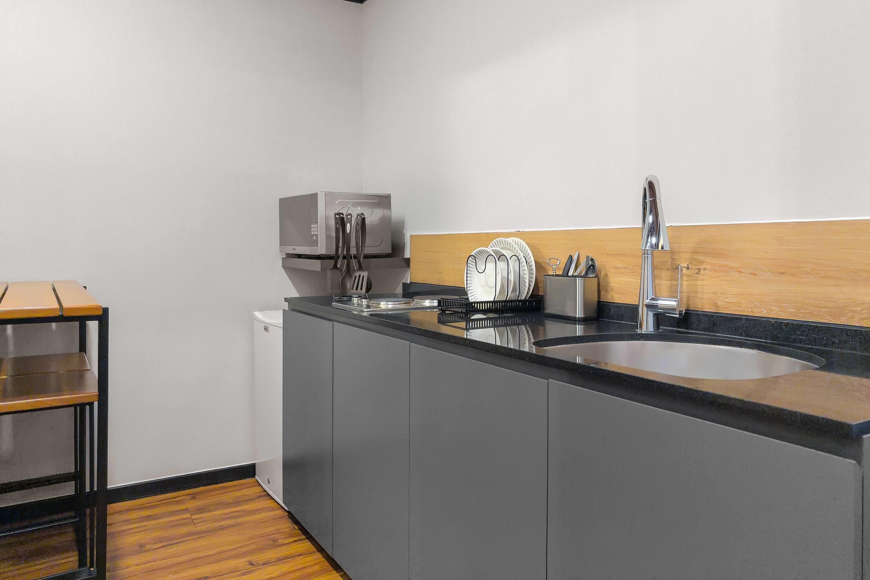 A modern kitchen with a black countertop, stainless steel appliances, and a wooden cabinet.