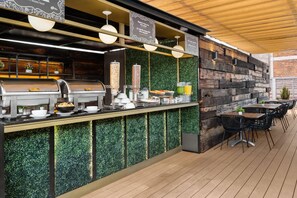An outdoor bar area with a grill, food dispensers, and seating. - Hotel MX mas centro CDMX, Trademark Collection by Wyndham (Mexico City)