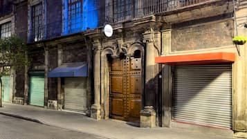 Um edifício com uma grande porta de madeira, uma marquise azul e uma placa acima da porta.