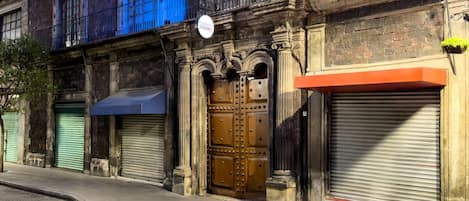 A building with a large wooden door, a blue awning, and a sign above the door.
