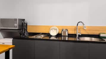 Una cocina moderna con microondas, estufa, pileta y utensilios.