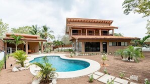 A two-story house with a swimming pool, surrounded by palm trees and a landscaped garden. - Flamingo Estates 18- 4 BR House with Pool (Flamingo)