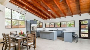A spacious kitchen with a large island, wooden ceiling beams, and large windows offering views of greenery. - Flamingo Estates 18- 4 BR House with Pool (Flamingo)