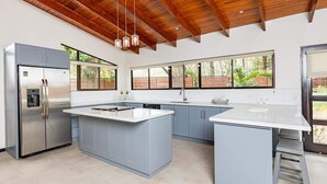 A modern kitchen with a large island, stainless steel appliances, and a wooden ceiling. - Flamingo Estates 18- 4 BR House with Pool (Flamingo)