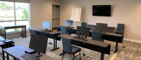 A modern office space with multiple workstations, each equipped with a computer and a chair.