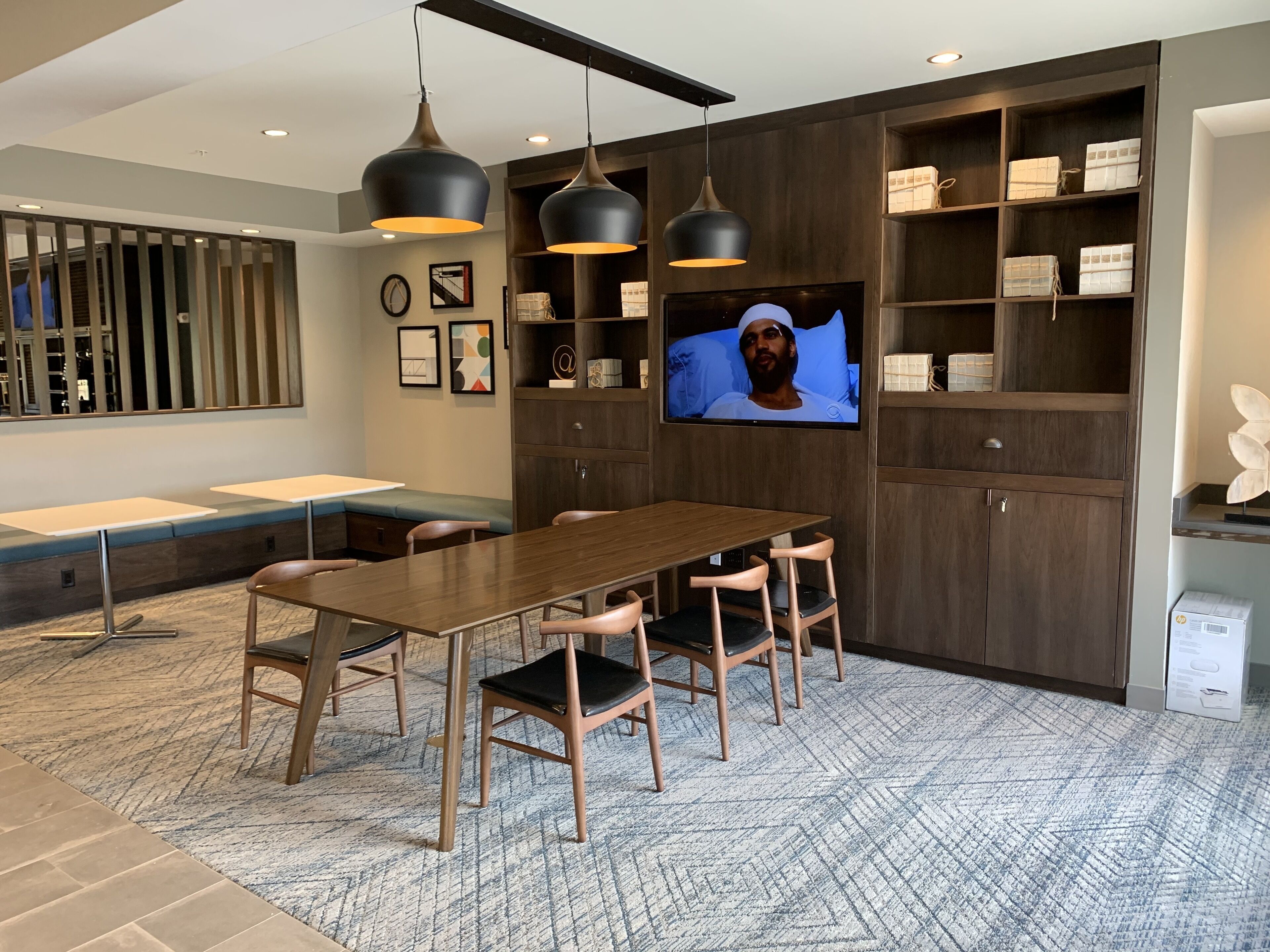 A modern meeting room with a long table, chairs, a TV, and built-in shelving.