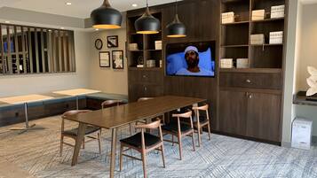 A modern meeting room with a long table, chairs, a TV, and built-in shelving.