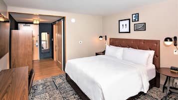 Une chambre d’hôtel avec un grand lit, une armoire en bois, un bureau et une petite table.