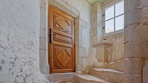 Eine Holztür mit geometrischen Mustern, eine Steinsäule und ein Fenster mit Blick.