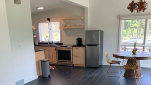 Una cocina moderna con piso de madera oscura, un refrigerador de acero inoxidable y un comedor con una mesa redonda y sillas.