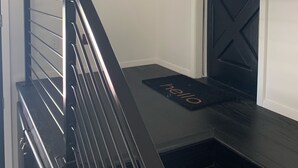 Una escalera con barandilla negra y felpudo negro que dice 'hello'.