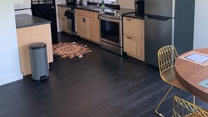 Una cocina moderna con armarios de madera, un refrigerador de acero inoxidable y un comedor con mesa y sillas.