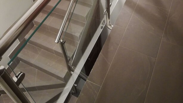 Moderni portaikko, jossa on lasikaiteet ja metalliset kaiteet.